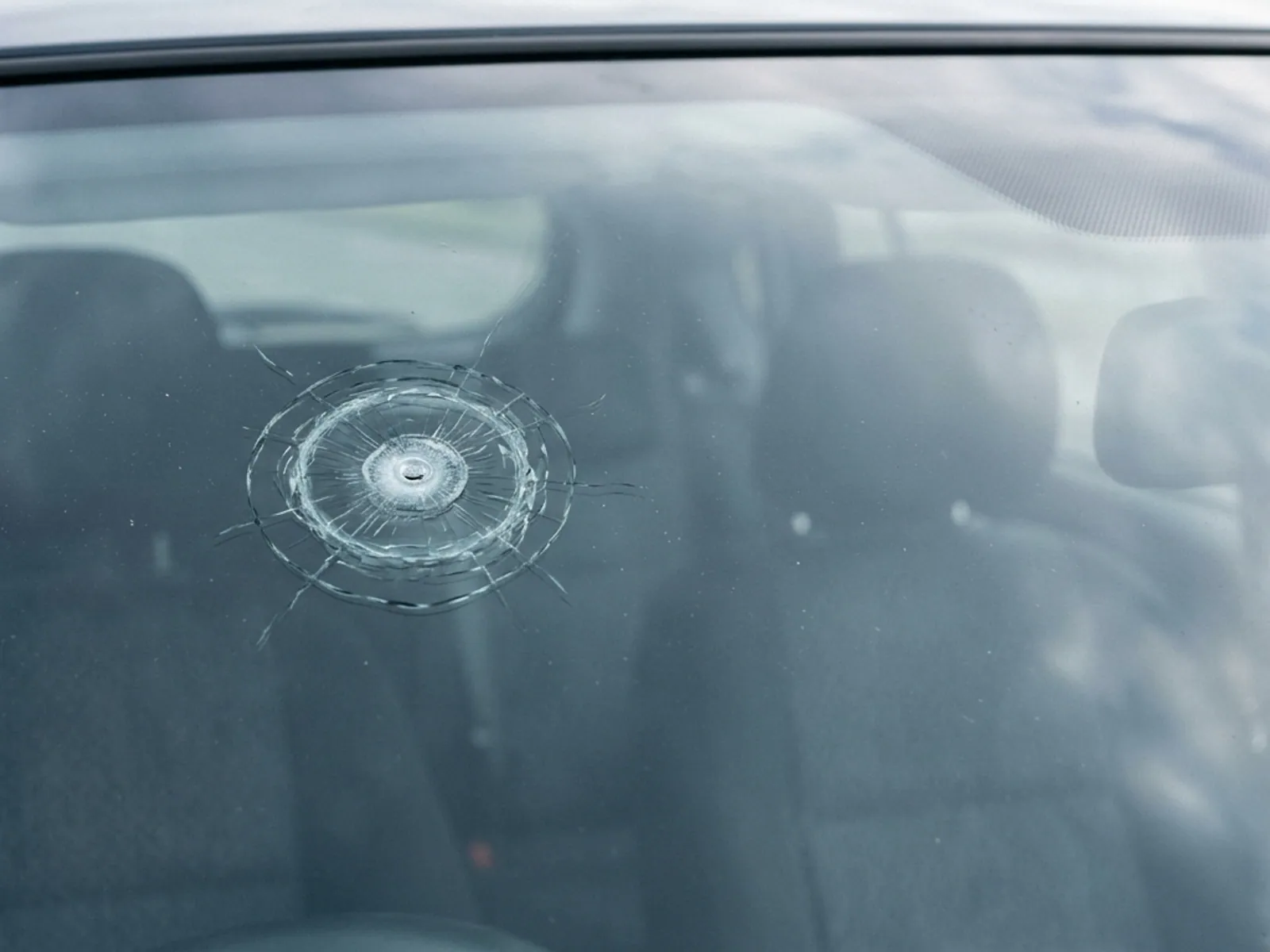 A circular bullseye chip in a windshield, showing as a small bright ring with a dark centre.